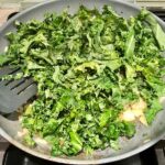 Cooking kale in pan for Shell Pasta with Italian Sausage and Kale. It's loaded with a salty homemade Chicken Italian Sausage flavored with garlic and fennel in a parmesan, garlic and kale sauce. 