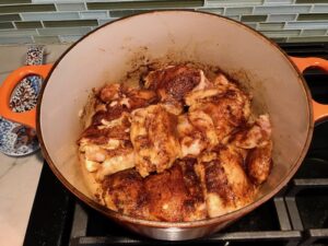 Chicken thighs in pot for Spanish Chicken and Rice. It's hearty, smokey, and delicious! Paprika spice blend rubbed chicken thighs are seared then cooked with rice, onions, carrots, garlic, tomatoes, and olives for unbelievable flavor! #easydinners #chickenrecipes