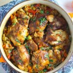 Spanish Chicken and Rice in pot is hearty, smokey, and delicious! Paprika spice blend rubbed chicken thighs are seared then cooked with rice, onions, carrots, garlic, tomatoes, and olives for unbelievable flavor! #easydinners #chickenrecipes