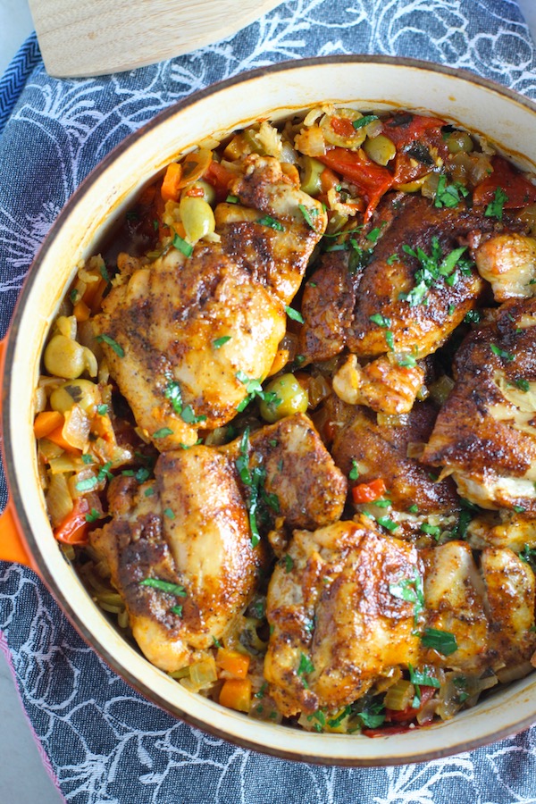 Spanish Chicken and Rice in pot is hearty, smokey, and delicious! Paprika spice blend rubbed chicken thighs are seared then cooked with rice, onions, carrots, garlic, tomatoes, and olives for unbelievable flavor! #easydinners #chickenrecipes