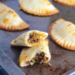 Ground Spiced Beef Empanadas on a pan. Flaky, buttery pastry on the outside with a savory, smokey, salty ground beef filling.
