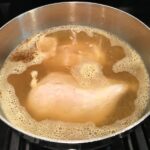 Chicken boiling for Creamy Chicken Green Enchilada Soup. It's creamy, hearty, slightly spicy with green chiles and smokey seasonings that bring so much depth.  Corn tortilla strips act like the noodles in this soup!