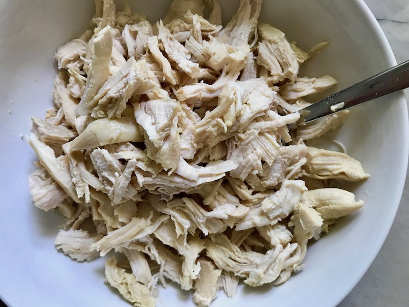 Shredded chicken for Creamy Chicken Enchilada Soup.  It's creamy, hearty, slightly spicy with green chiles and smokey seasonings that bring so much depth.  Corn tortilla strips act like the noodles in this soup!