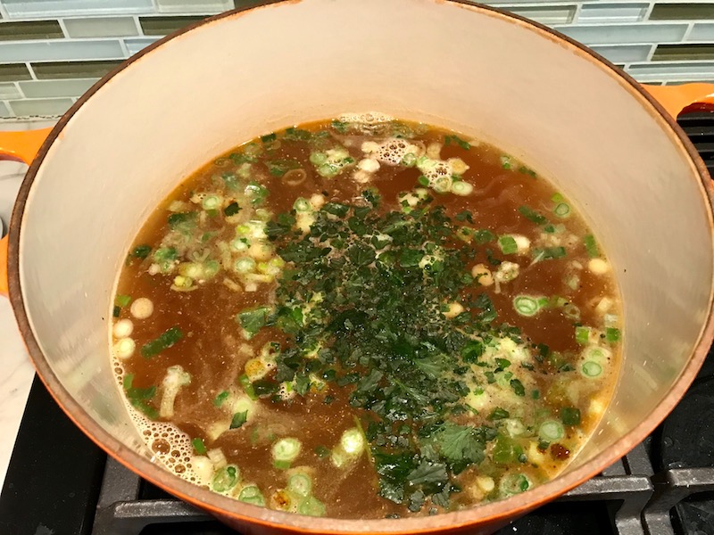 Cilantro added to broth for Creamy Chicken Enchilada Soup. It's creamy, hearty, slightly spicy with green chiles and smokey seasonings that bring so much depth.  Corn tortilla strips act like the noodles in this soup!