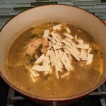 Chicken and tortillas added to soup for Creamy Chicken Green Enchilada Soup. It's creamy, hearty, slightly spicy with green chiles and smokey seasonings that bring so much depth.  Corn tortilla strips act like the noodles in this soup!