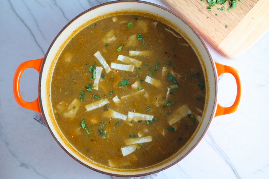 Creamy Chicken Enchilada Soup in a pot. It's creamy, hearty, slightly spicy with green chiles and smokey seasonings that bring so much depth.  Corn tortilla strips act like the noodles in this soup!