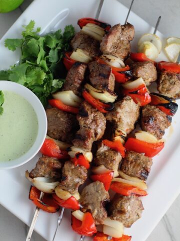 Garlic Steak Kabobs with red pepper and onion on platter with a Creamy Cilantro Sauce! #beefkabobs #steakkabobs