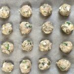 Raw Ground Chicken Greek Meatballs on a pan. These meatballs have garlic, feta, parsley, and oregano