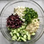 Cucumber, Kalamata Olives, Feta Cheese, Scallions, and orzo all separate in bowl for Greek Orzo Salad.