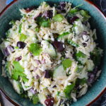 Greek Lemon Orzo Salad with Kalamata Olives, Cucumbers, and Feta Cheese in a bowl with spoon on side. It's mixed with a creamy lemon dressing that's bright and light!