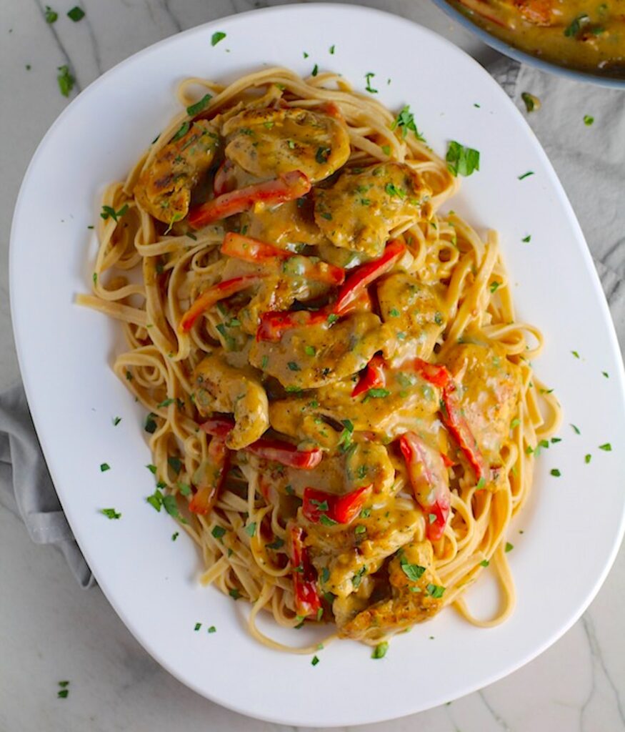 Tarragon Mustard Sauce for Chicken Without Cream with red peppers over linguine pasta on platter with parsley sprinkled on top. It gets so much flavor from dijon mustard, tarragon, garlic, and onion. It's an easy-to-whip-up any night dinner!