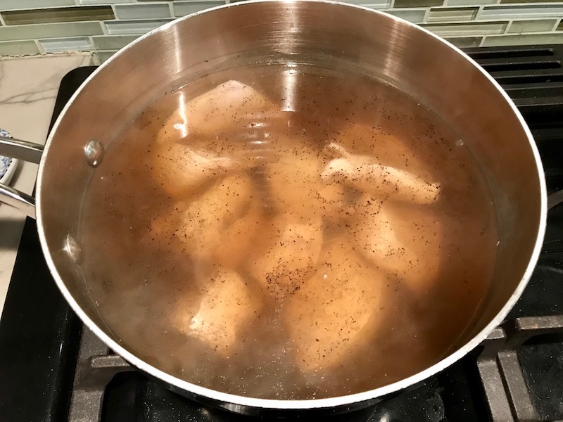 Chicken boiling in water in pot for a BBQ Chicken Pizza Recipe