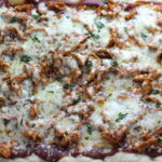 Whole BBQ Chicken Pizza in a rectangle sheet pan with homemade pizza crust, tangy and creamy BBQ sauce, hearty shredded chicken, cheddar cheese and coleslaw on top!   