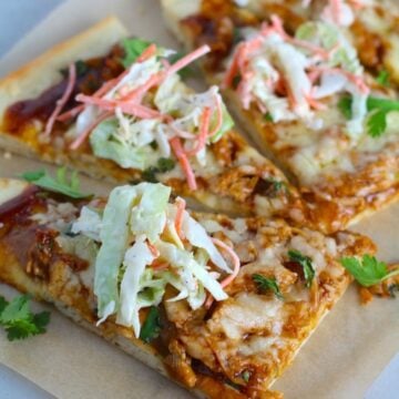Sliced BBQ Chicken Pizza recipe with coleslaw and cilantro on top. It has homemade pizza crust, tangy and creamy BBQ sauce, hearty shredded chicken, cheddar cheese and coleslaw on top!   