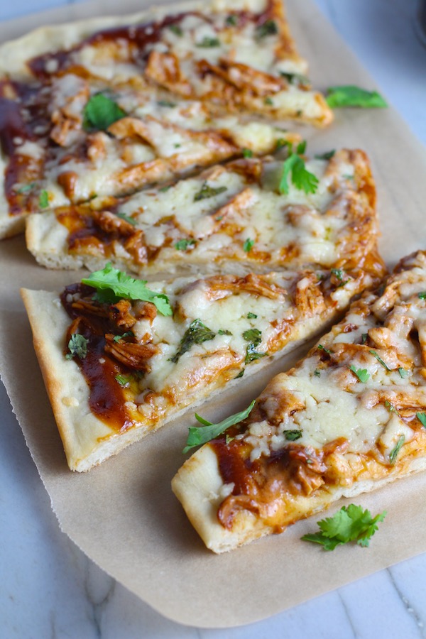 Sliced BBQ Chicken Pizza Recipe with cilantro on top. It has homemade pizza crust, tangy and creamy BBQ sauce, hearty shredded chicken, cheddar cheese and coleslaw on top!   