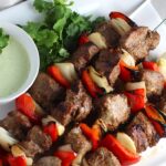 Garlic Steak Kabobs with red pepper and onion on platter with a Creamy Cilantro Sauce! #beefkabobs #steakkabobs