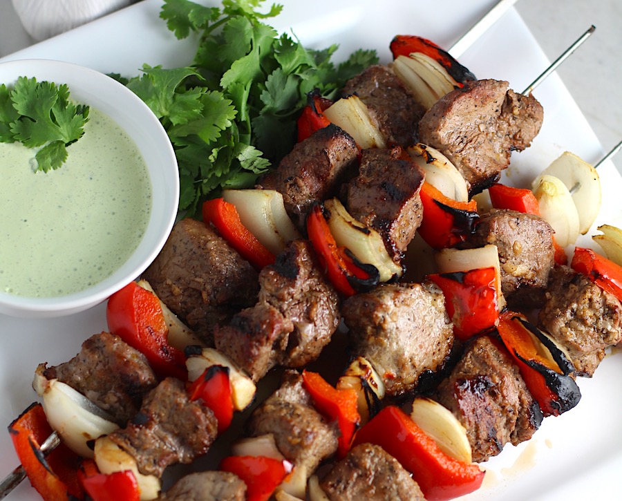 Garlic Steak Kabobs with red pepper and onion on platter with a Creamy Cilantro Sauce! #beefkabobs #steakkabobs