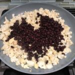 Black beans and Cauliflower florets in pan for Quinoa Black Bean Burritos. Packed with protein and fiber, but also cheese, tomato, cilantro, and sour cream!  The vegetarian 'meat' is taco-seasoned quinoa, black beans, and cauliflower.