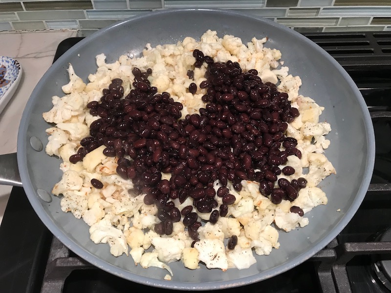 Black beans and Cauliflower florets in pan for Quinoa Black Bean Burritos. Packed with protein and fiber, but also cheese, tomato, cilantro, and sour cream!  The vegetarian 'meat' is taco-seasoned quinoa, black beans, and cauliflower.
