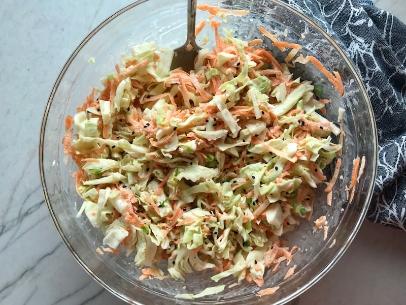 Coleslaw mixed in a clear bowl on counter for BBQ Chicken Flatbread Pizza recipe.
