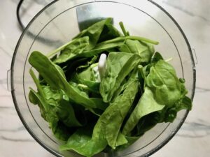 Basil, chives, and spinach in food processor for Green Rice Recipe. It takes white rice from plain to amazing with just 5 ingredients. Filled with herbs and spinach, it has the perfect herby flavor.