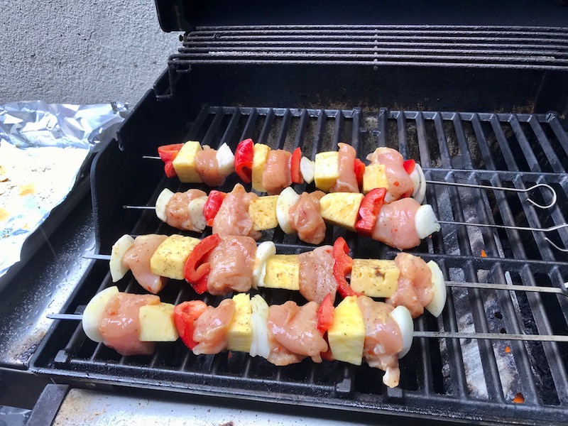 Raw Sweet and Sour Chicken Kabobs with pineapple, onion, and red pepper on gas grill..