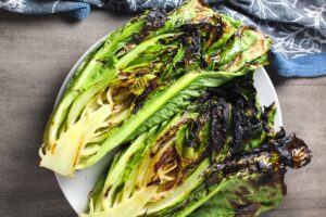 Grilled romaine lettuce halves for Flank Steak Salad Recipe with halved grape tomatoes, and creamy basil yogurt dressing.