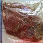 Steak and marinade in plastic bag for Flank Steak Salad Recipe with halved grape tomatoes, and creamy basil yogurt dressing.