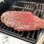 Flank steak on gas grill for Flank Steak Salad Recipe with halved grape tomatoes, and creamy basil yogurt dressing.