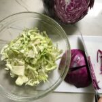 knife slicing purple cabbage with white cabbage in bowl on side for Korean Beef Tacos with flavorful Korean beef, crunchy Sesame Cabbage Slaw and a creamy, cool, Cilantro Lime Sriracha sauce!