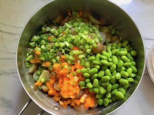 Edamame, orange pepper, celery, and scallions in pot with cooked potatoes for Red Potato Salad Recipe with Edamame and Harissa. It's creamy, crunchy, meaty, tangy, peppery, salty, and oh, it's UNBELIEVABLE!