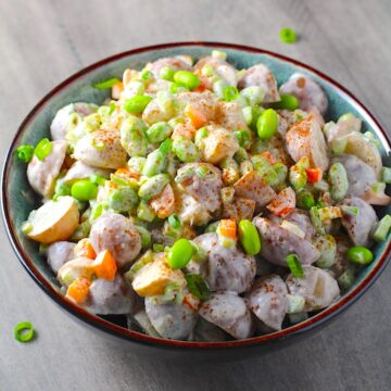 Red Skin Potato Salad Recipe with Edamame and Harissa in a bowl on table. It's creamy, crunchy, meaty, and delicious.