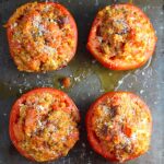 Stuffed Tomatoes on sheet pan on counter with chorizo, quinoa, parmesan cheese, chives, garlic, and oregano are simply divine! 
