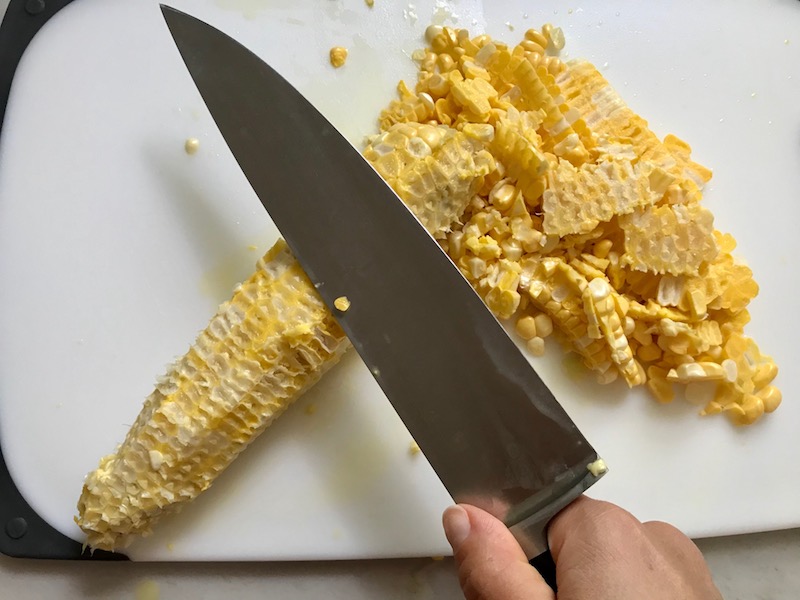 Back of knife scraping the corn cob for Creamy Corn and Blackened Chicken skillet dinner