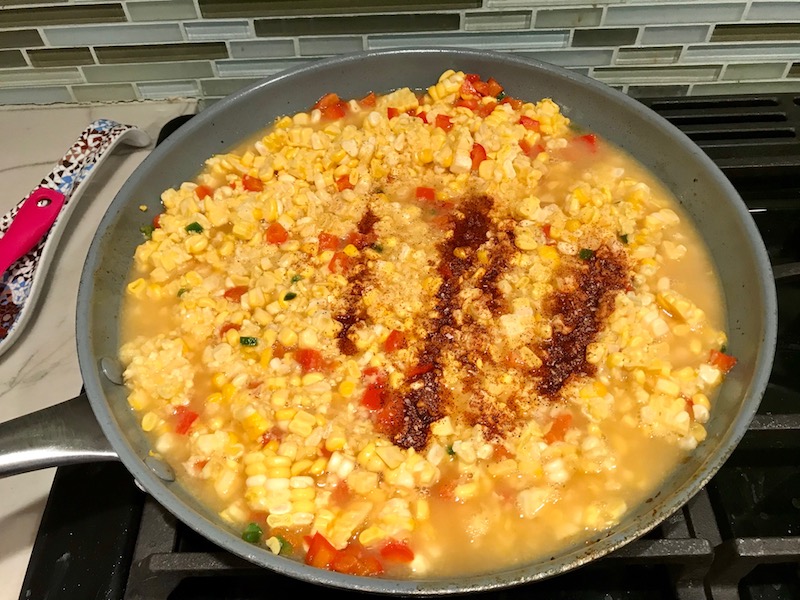 Seasoning on top of cream corn in pan for Creamy Corn and Blackened Chicken skillet dinner