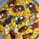 Creamy Corn and Blackened Chicken with feta and cilantro on top in a pan.