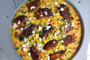 Creamy Corn and Blackened Chicken with feta and cilantro on top in a pan.