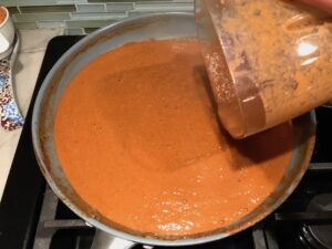 Pureed mole sauce being poured from blender to pan for Chicken Mole Enchiladas. The Mole sauce has unsweetened chocolate, tomatoes, green chilis, garlic, adobo sauce, and spices blend harmoniously!