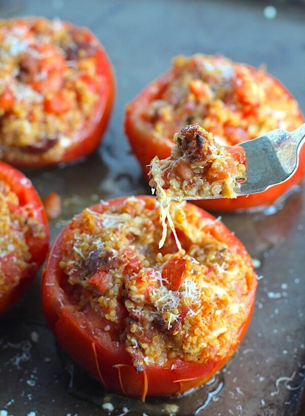Stuffed Tomatoes on sheet pan on counter with chorizo, quinoa, parmesan cheese, chives, garlic, and oregano are simply divine! 