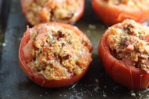 Stuffed Tomatoes on sheet pan on counter with chorizo, quinoa, parmesan cheese, chives, garlic, and oregano are simply divine! 