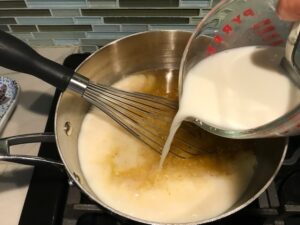 Pouring milk slurry into pot for Broccoli Cheese Quinoa Bake It's a comfy cozy casserole that's perfect to make ahead for a simple weeknight side or main dish.