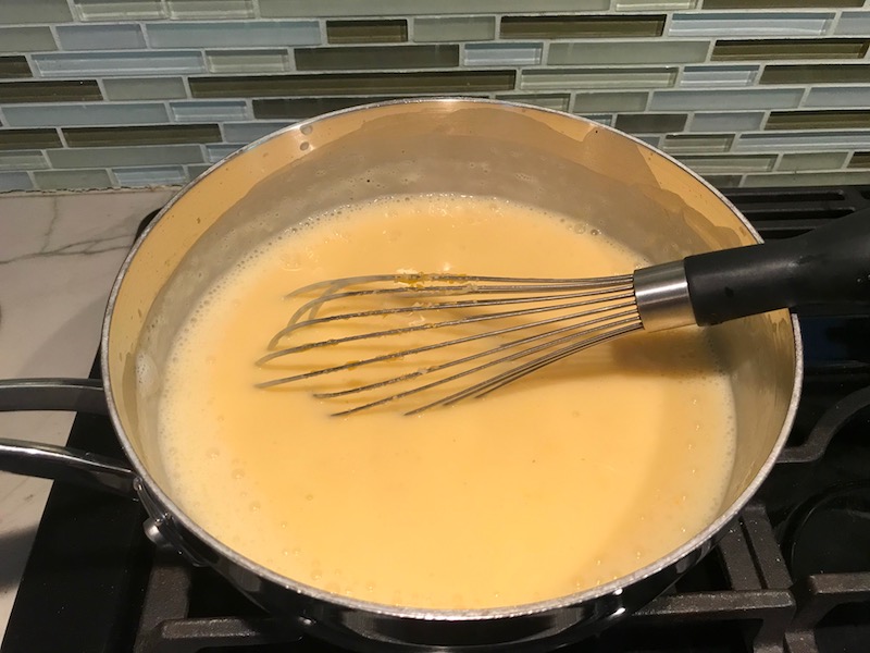 Whisk in Cheese sauce in pot on stove for the Broccoli Quinoa Casserole recipe.