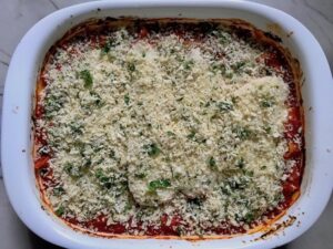 Chicken Parmesan Pasta Bake in casserole pan. It cooks entirely in one casserole dish, including the pasta! Shell pasta in flavorful, tangy tomato sauce is topped with zucchini, chicken, mozzarella, parm, and crunchy breadcrumb topping.