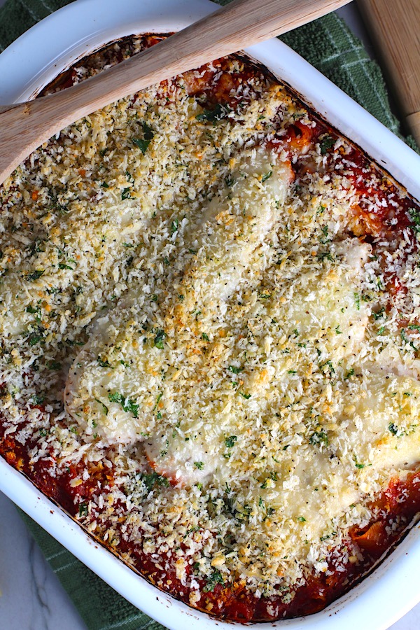 Chicken Parmesan Pasta Bake in casserole pan.  It cooks entirely in one casserole dish, including the pasta! Shell pasta in flavorful, tangy tomato sauce is topped with zucchini, chicken, mozzarella, parm, and crunchy breadcrumb topping.
