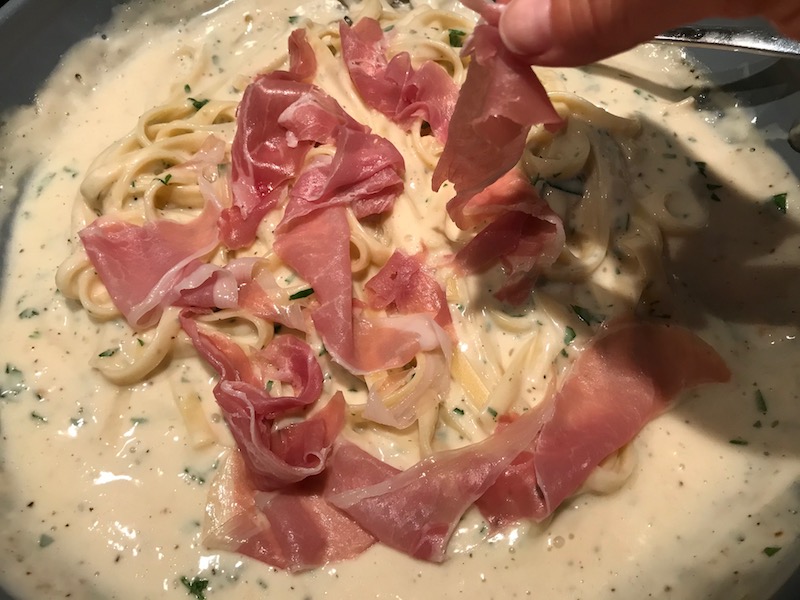Adding prosciutto to pasta alfredo in pan for Light and Easy Fettuccine Alfredo with Prosciutto