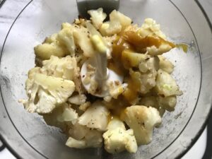 cooked cauliflower and other ingredients in food processor for Roasted Garlic Cauliflower Mash.