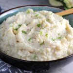 Mashed Roasted Cauliflower in a bowl with spoon. The texture is perfectly creamy and along with the flavor, mimics mashed potatoes.One of the best holiday side dishes
