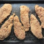 Raw chicken coated in bacon breadcrumbs on pan for Oven Fried Chicken Breast. The chicken is coated with Bacon Crumbs and Honey and it's healthier because it's baked, not fried, but still gives you all of the crispy, crunchy goodness!  It also gives you sweet and salty crunch with the addition of honey and bacon!