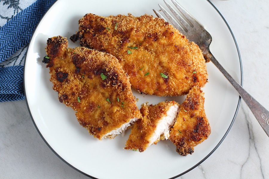 Oven Fried Chicken Breast cut on plate with fork. The chicken is coated with Bacon Crumbs and Honey and it's healthier because it's baked, not fried, but still gives you all of the crispy, crunchy goodness!  It also gives you sweet and salty crunch with the addition of honey and bacon!