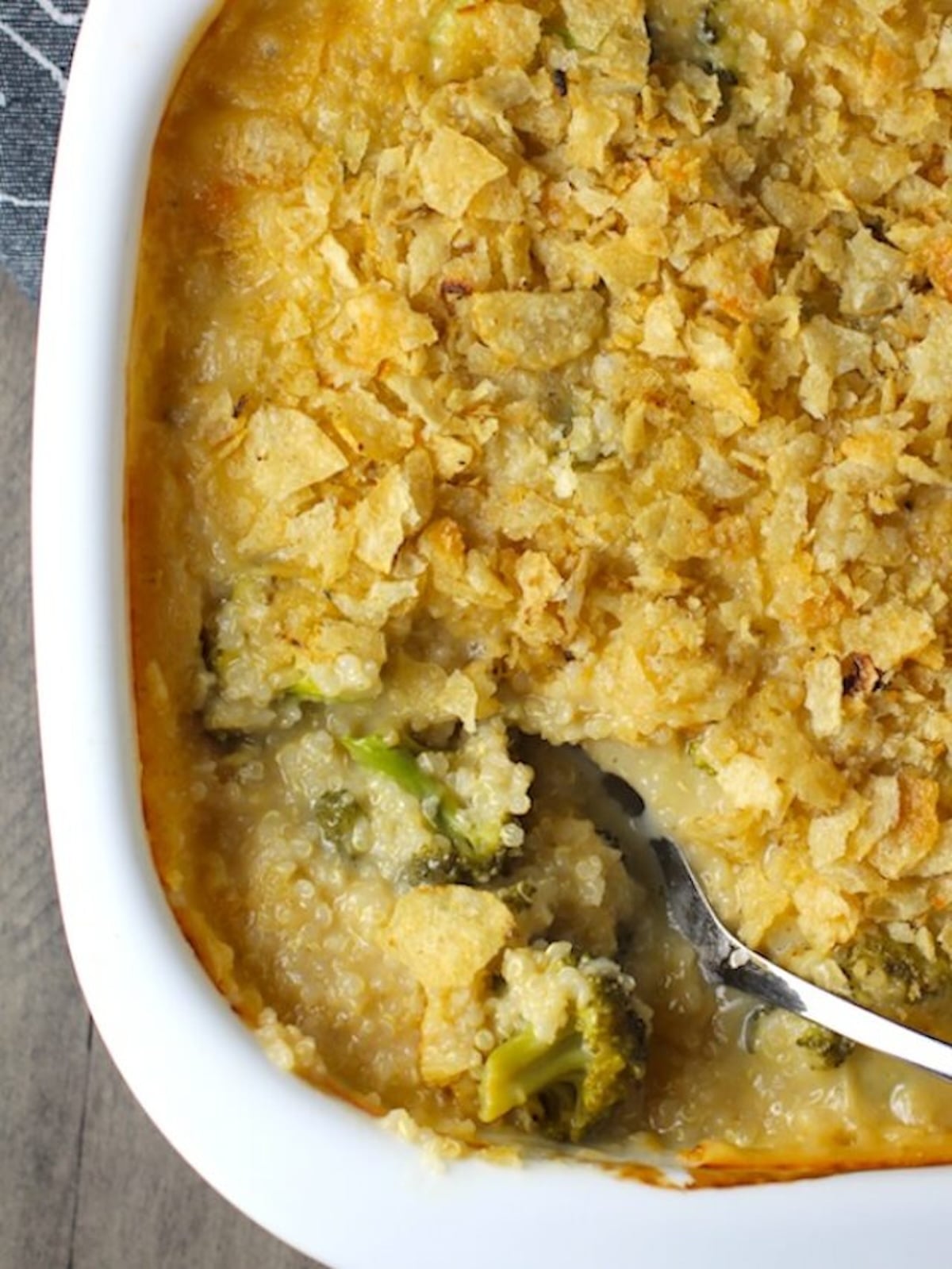 Spoon scooping Broccoli Cheese Quinoa Bake with potato chips on top. It's a comfy cozy casserole that's perfect to make ahead for a simple weeknight side or main dish.